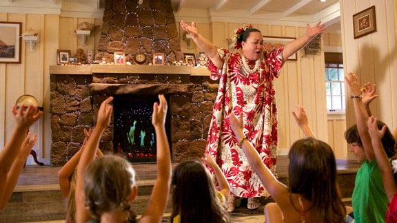 A woman in a floral dress telling a story to small children