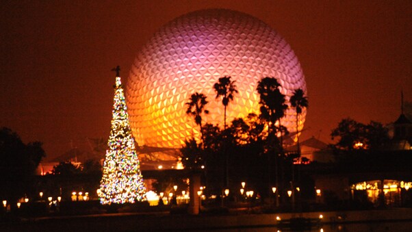 A brightly lit Christmas tree in front of Spaceship Earth at Epcot in Florida
